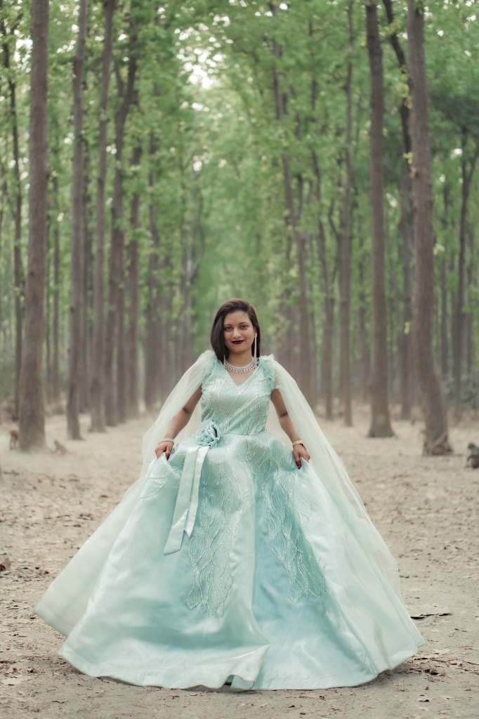 Bride Yasmin in flared mint green gown walking through tall forest path during pre-wedding shoot
